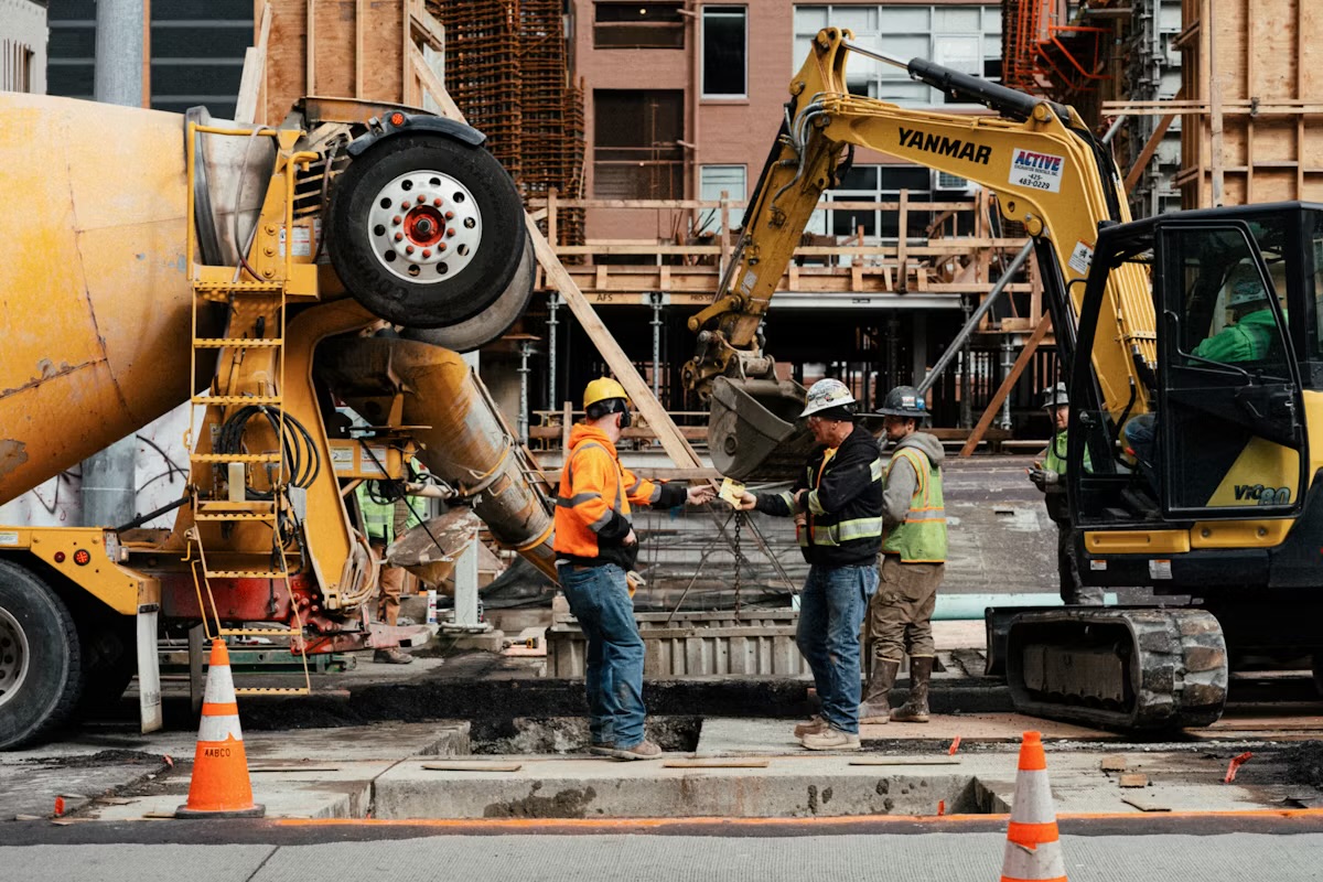 Construction site with concrete mixer, excavator, and workers