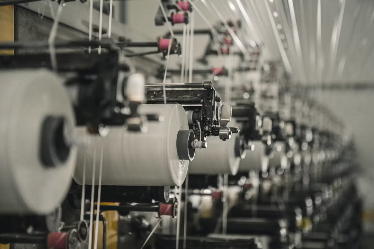 Textile manufacturing machinery with yarn spools and threading equipment